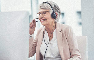 Smiling nurse wears headset while chatting in front of a computer